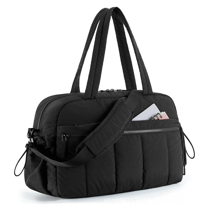 Black quilted shoulder travel tote bag with adjustable strap and front zip pockets