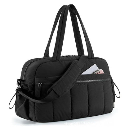 Black quilted shoulder travel tote bag with adjustable strap and front zip pockets