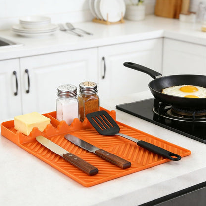 Orange silicone spatula tools mat with textured grooves, slots for utensils and drip trough