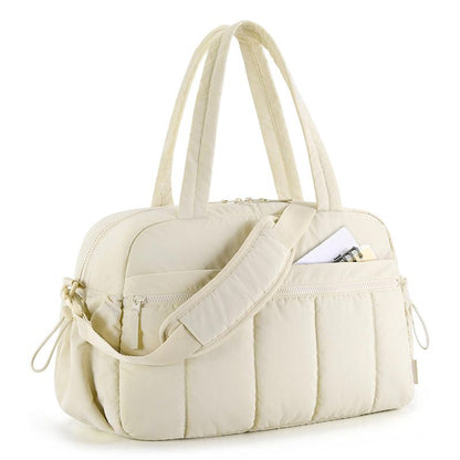Beige quilted shoulder travel tote bag with wide strap and front zip pockets