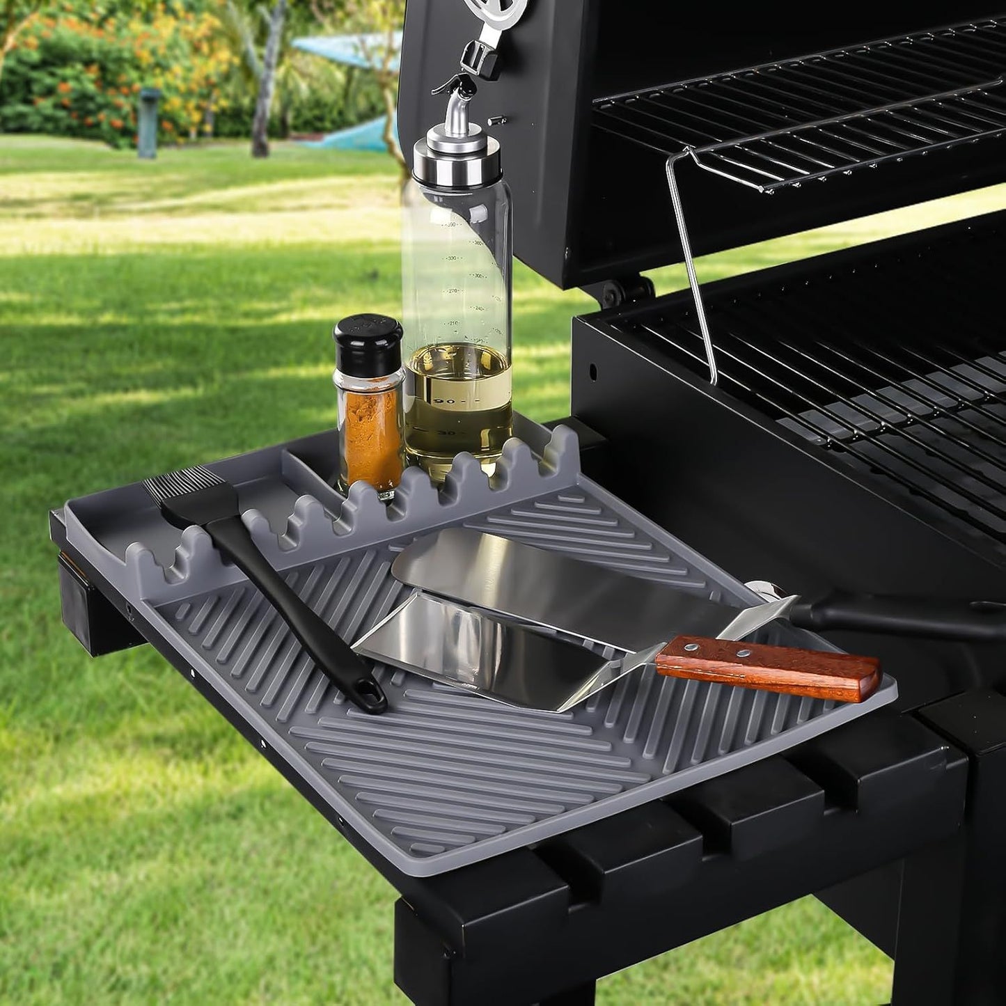 Gray silicone tools mat on grill shelf with utensil slots and drip pad
