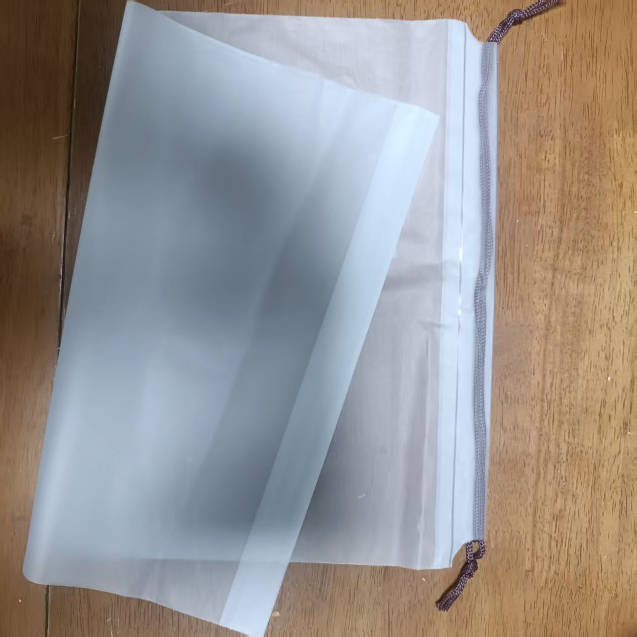 Transparent drawstring travel storage bag with open top and dark cord tie