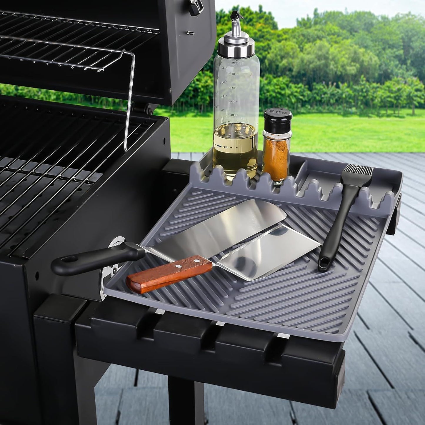 Gray silicone tools mat with ribbed drip pad and utensil slots beside grill