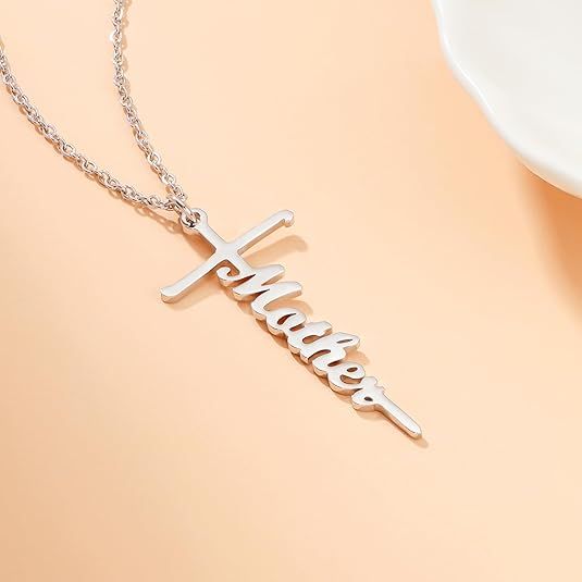 Silver cross pendant necklace with a cursive word charm on a delicate chain.