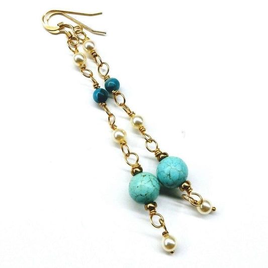 Gold tone long drop earrings with turquoise beads, white pearls, and dangling charms.