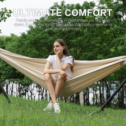 Cream double hammock on black stand; woman relaxing outdoors in a yard.