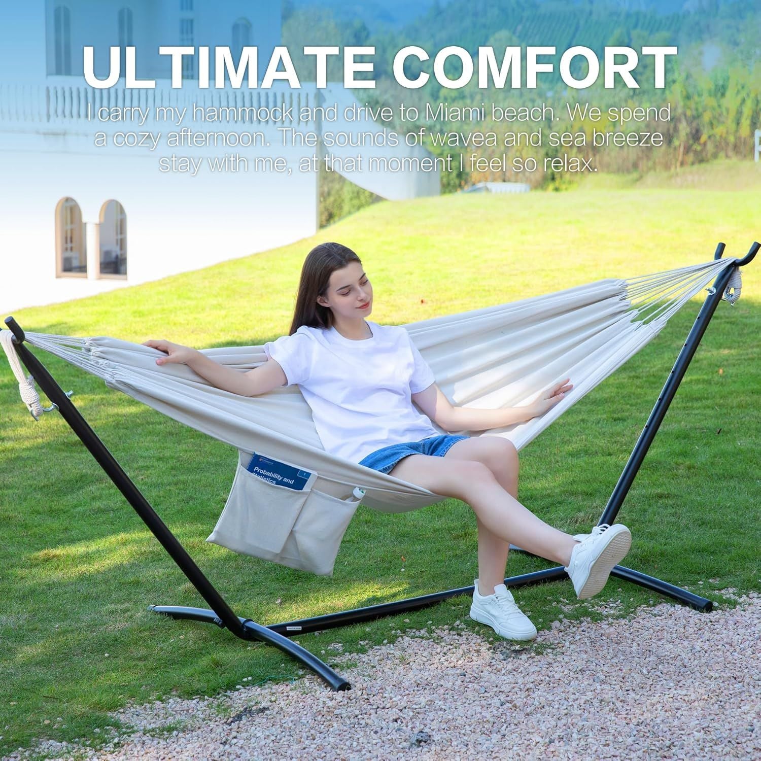 Double hammock on black steel stand with white fabric; woman sitting outdoors.