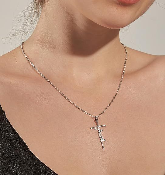 Silver cross pendant necklace with cursive charm worn close to the neck
