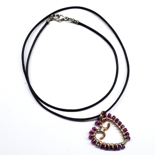 Wire-wrapped open-heart crystal necklace with purple stones on black cord