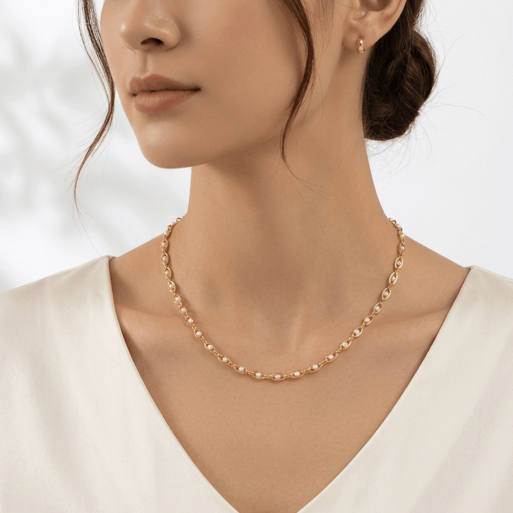 Gold-tone seed pearl necklace worn at collarbone with short curved pearl chain
